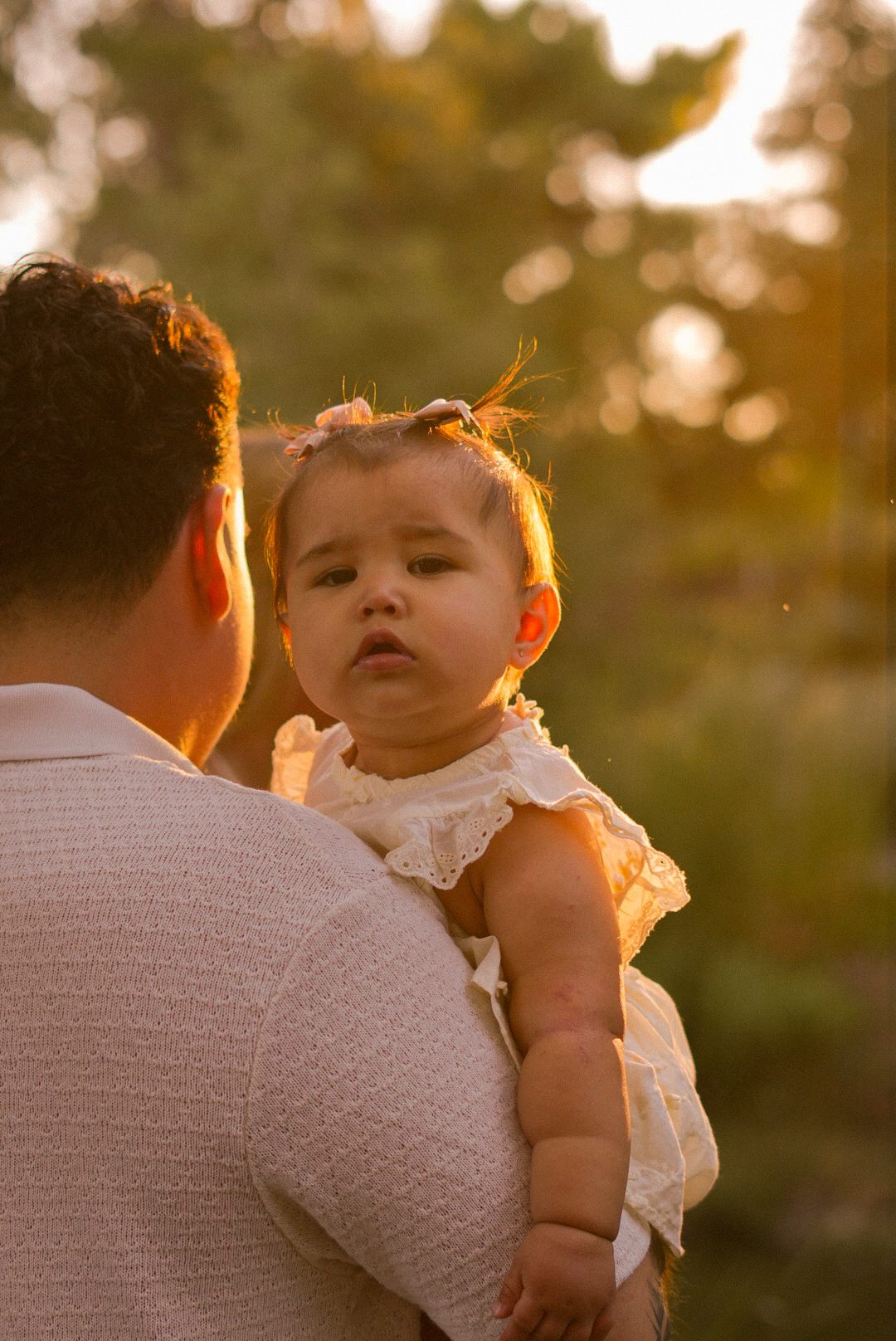A little one held close by dad at golden hour