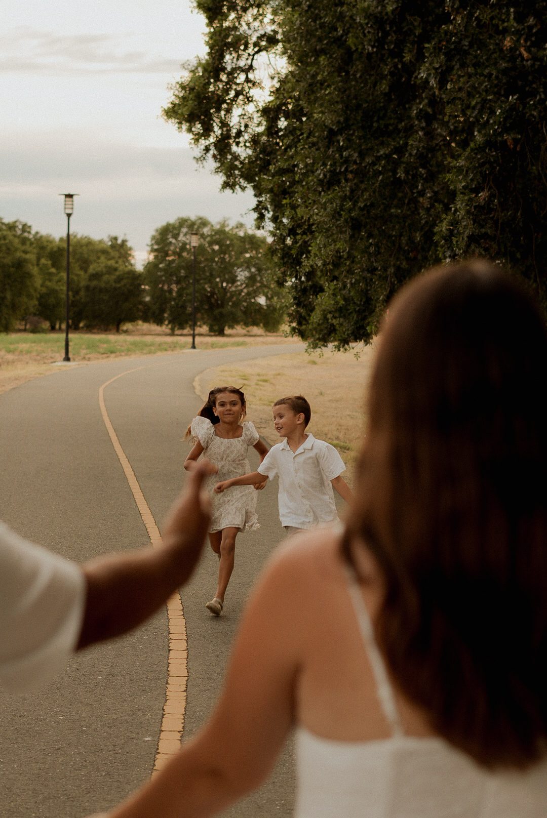 Kids running toward mom on a park path